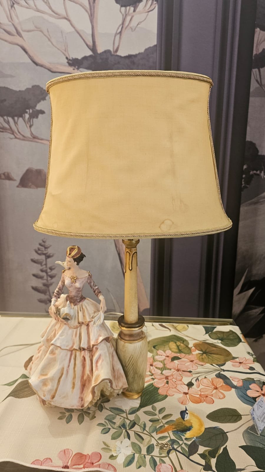 paralume crema, su tavolo floreale e bambola di dama con abito lungo a fianco, usurato e da restaurare